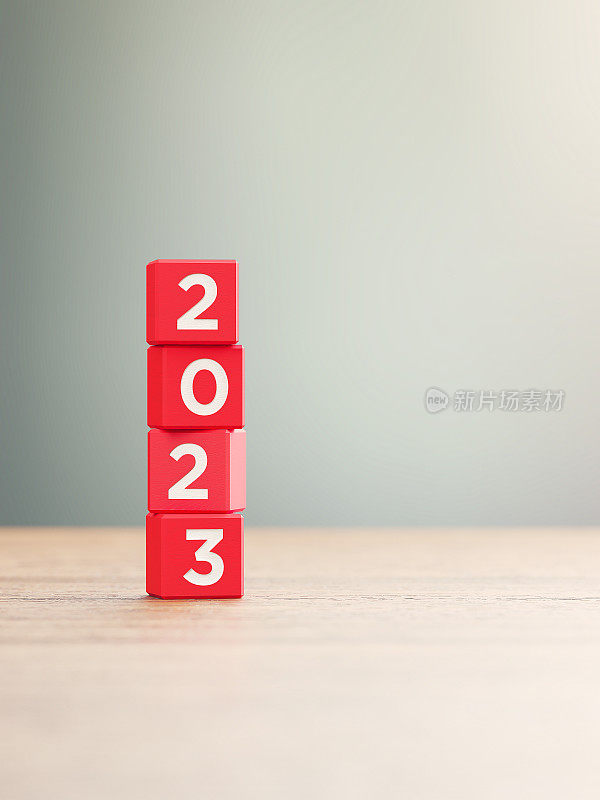 2023概念- 2023写的红色木块坐在木表面前面一个散焦背景